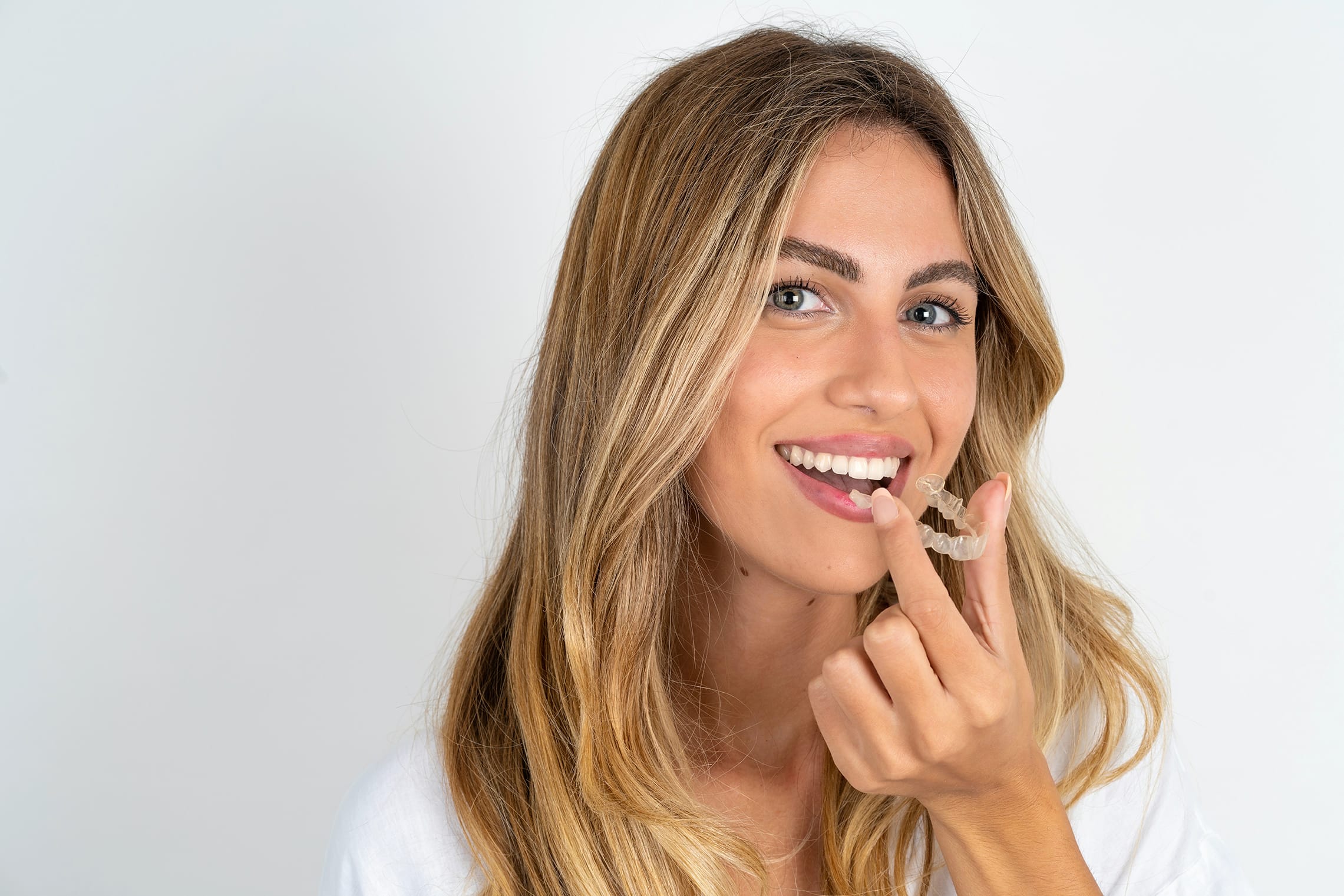 woman placing invisalign dental aligners from Vivere Meliora Dentistry